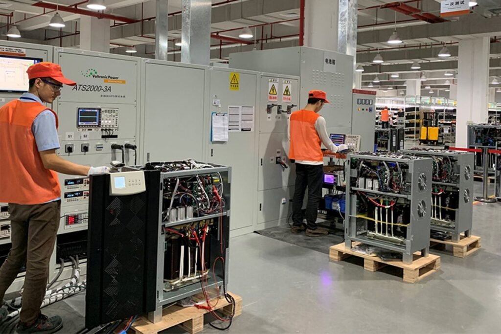Voltronic Power factory workers operating advanced production equipment